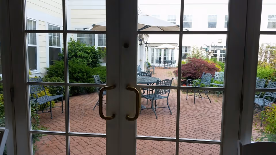 Outdoor brick patio courtyard with metal tables and chairs viewed through glass doors