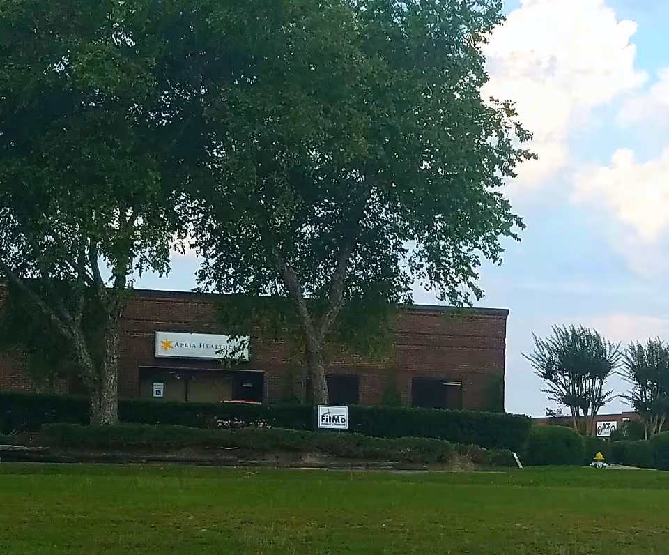 Exterior view of a brick facility with trees and an Apria Healthcare sign.