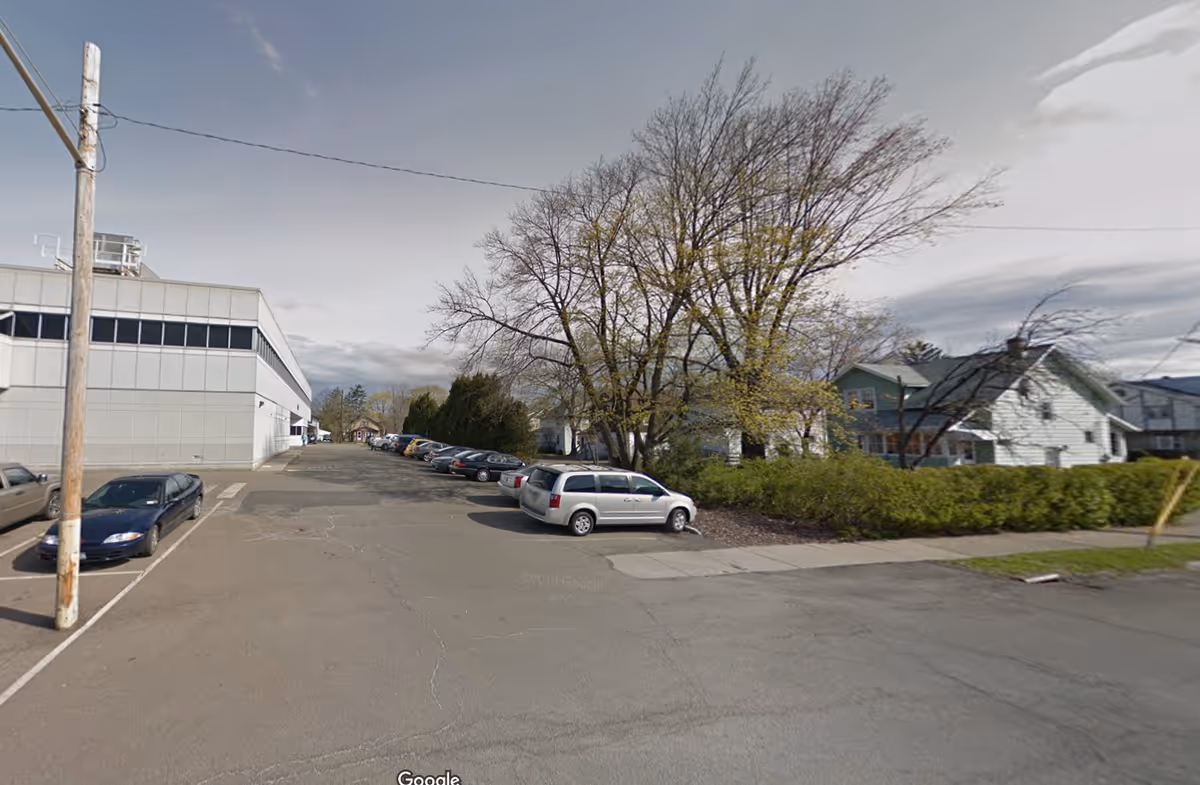 Exterior view of a building with a parking lot and trees along the street.