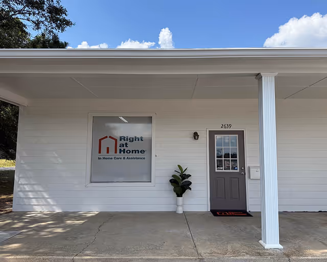 Exterior of a single-story white building with a door, porch column, and Right at Home sign.