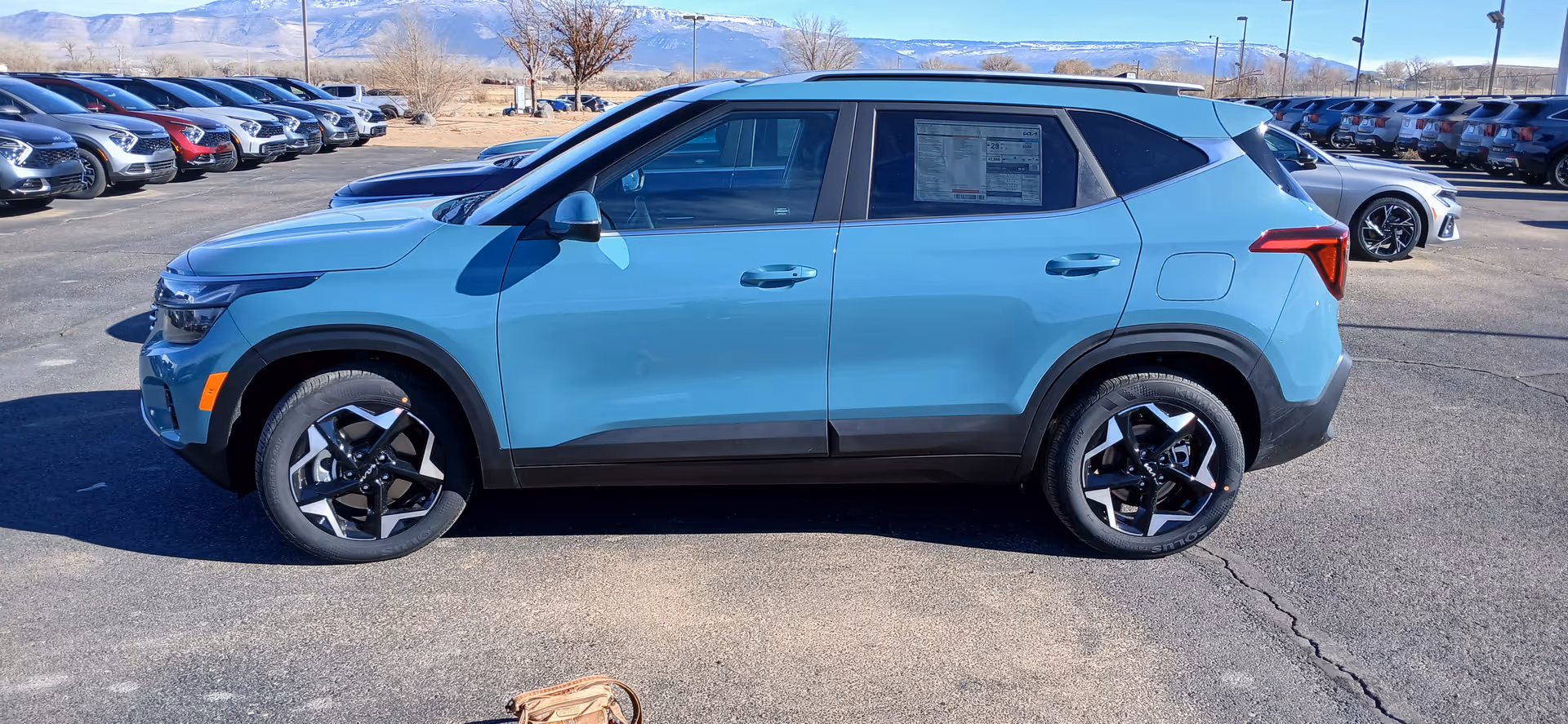 Blue SUV parked in an outdoor car lot with other vehicles.