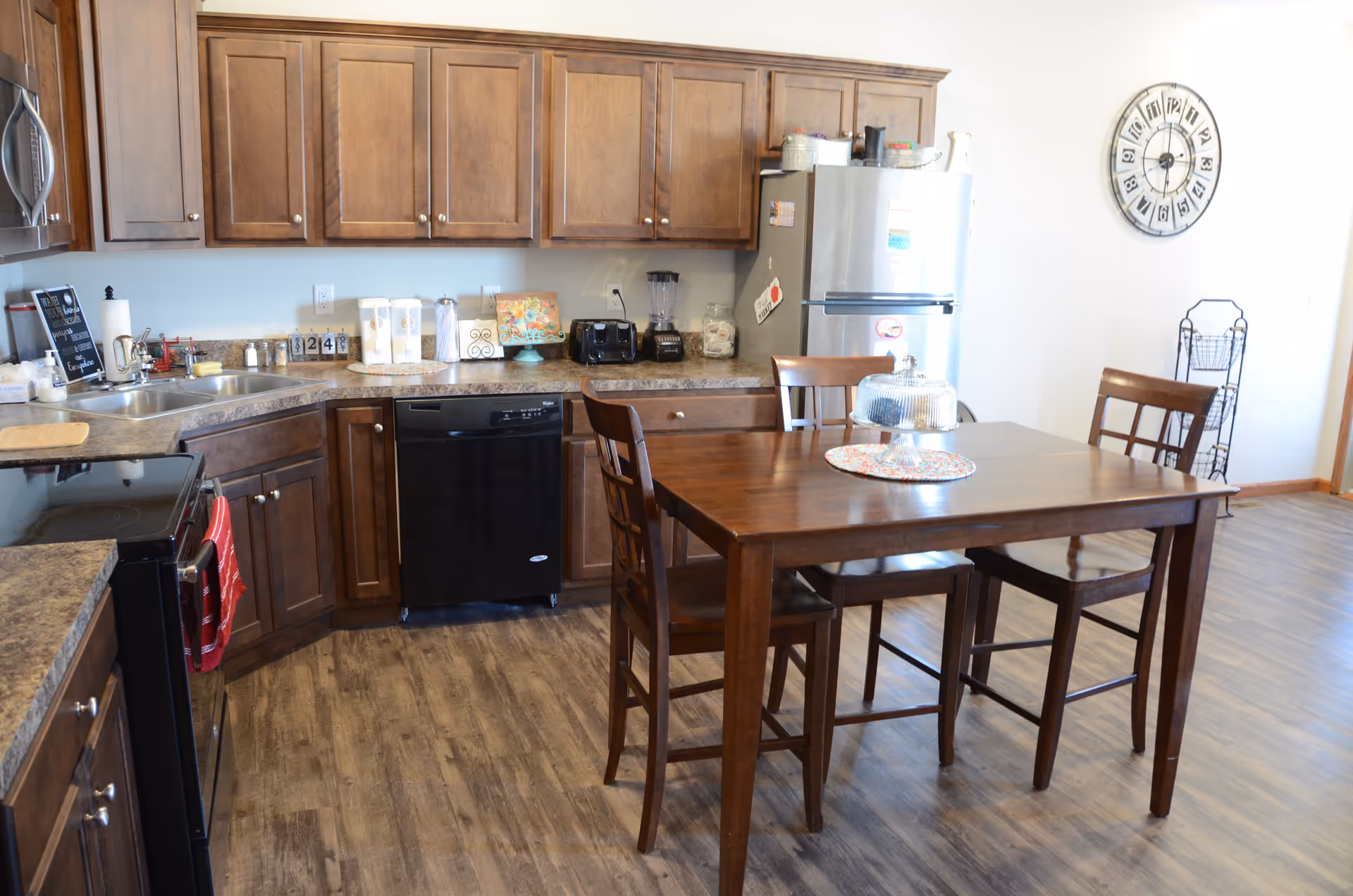 Open kitchen with wooden cabinets, stainless appliances, and a dining table.