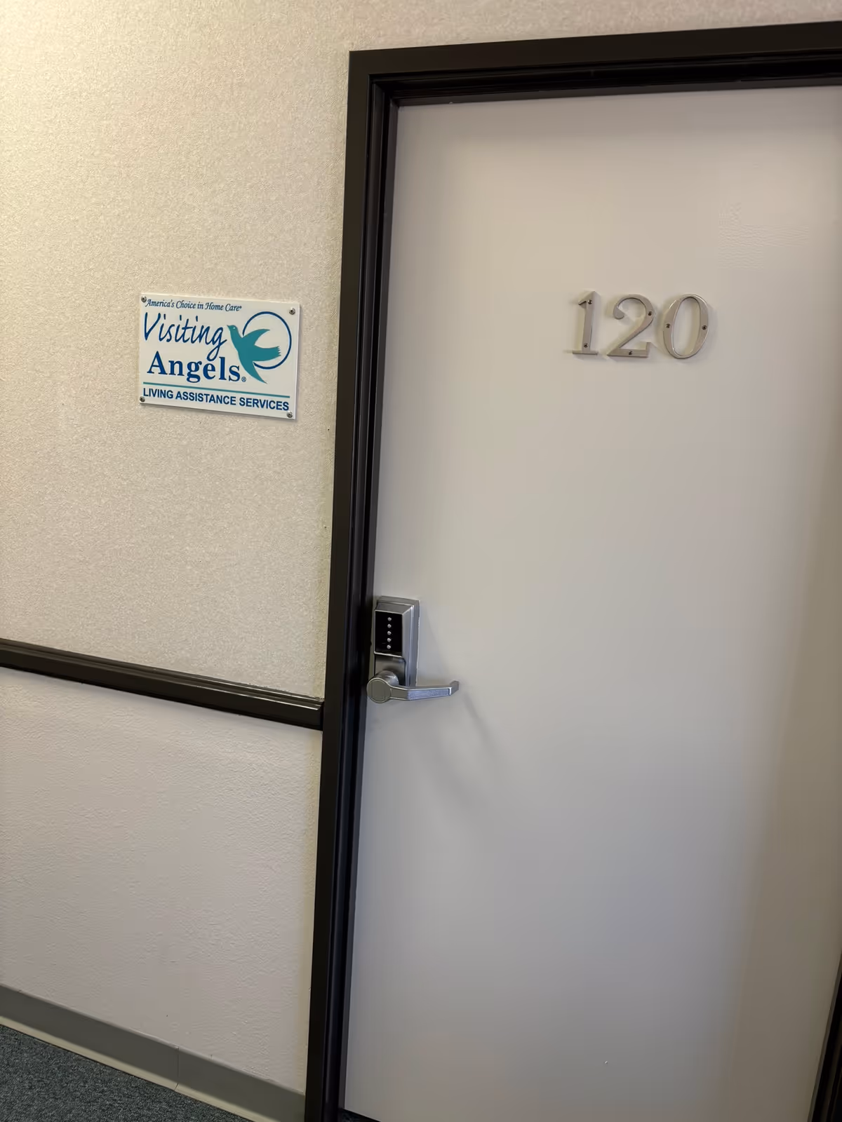 Interior hallway with a plain door labeled 120 and a Visiting Angels sign.