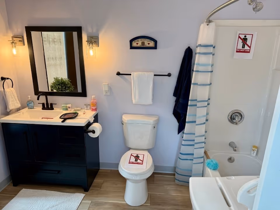 Bathroom in a Senior Helpers facility with sink, toilet, and shower.