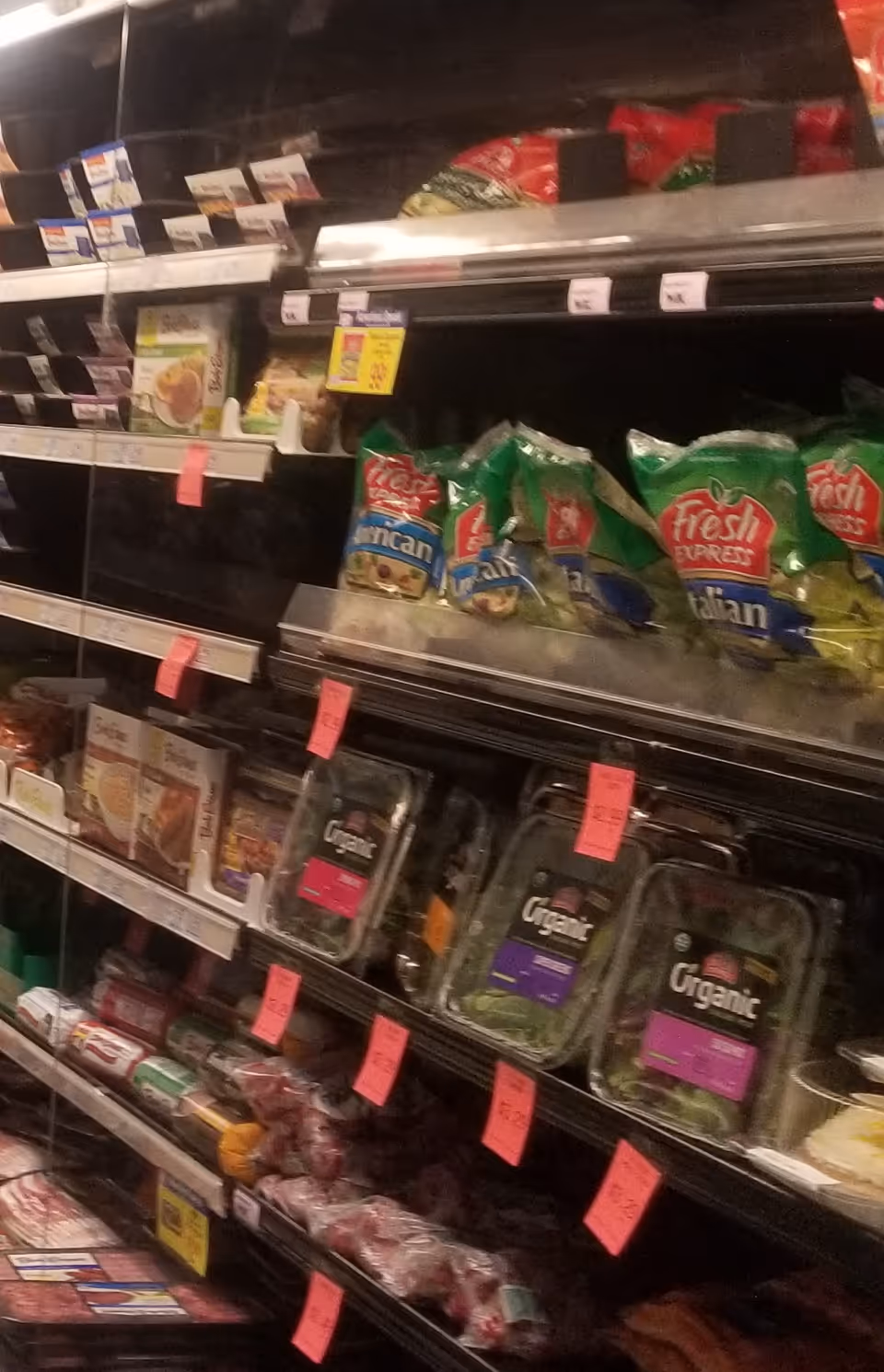 Aisle of shelves with packaged snacks and pink price tags at Discount Drug Mart.