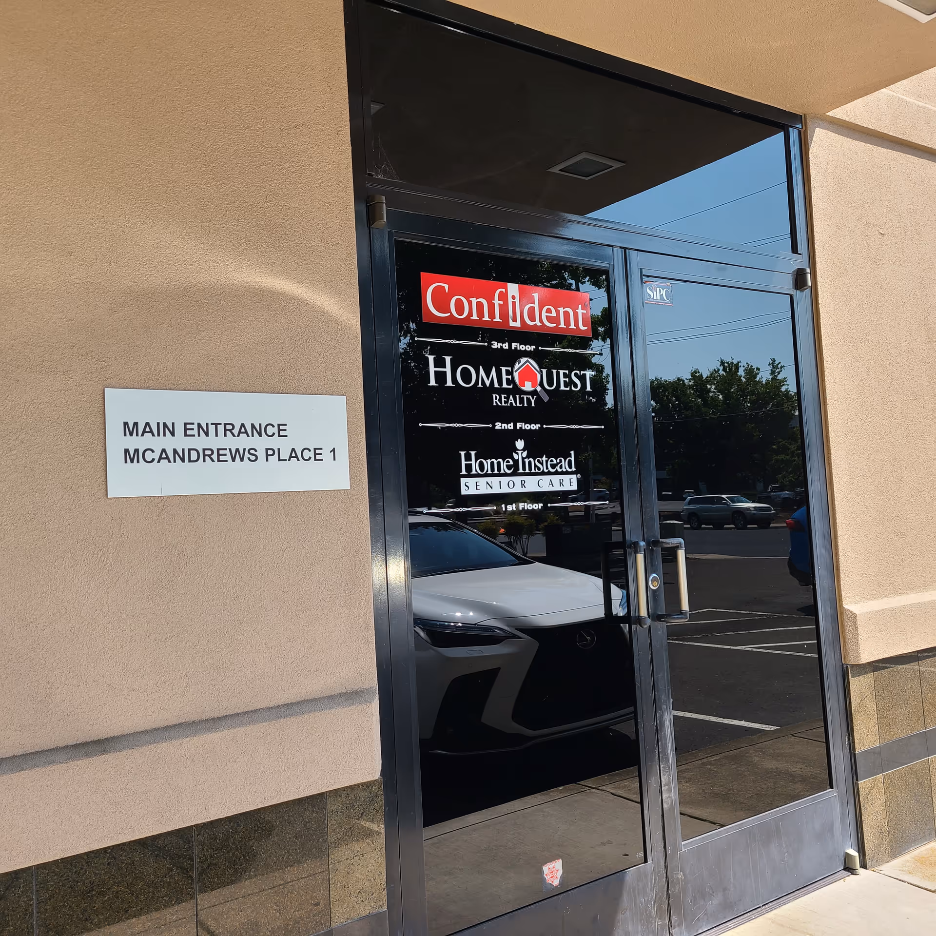 Glass entrance door with signs for Confident, Home Instead, and Main Entrance McAndrews Place 1