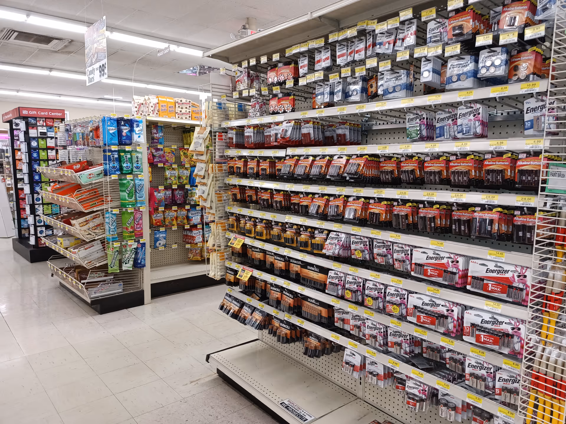 Bright drugstore aisle with battery shelves and assorted small products.