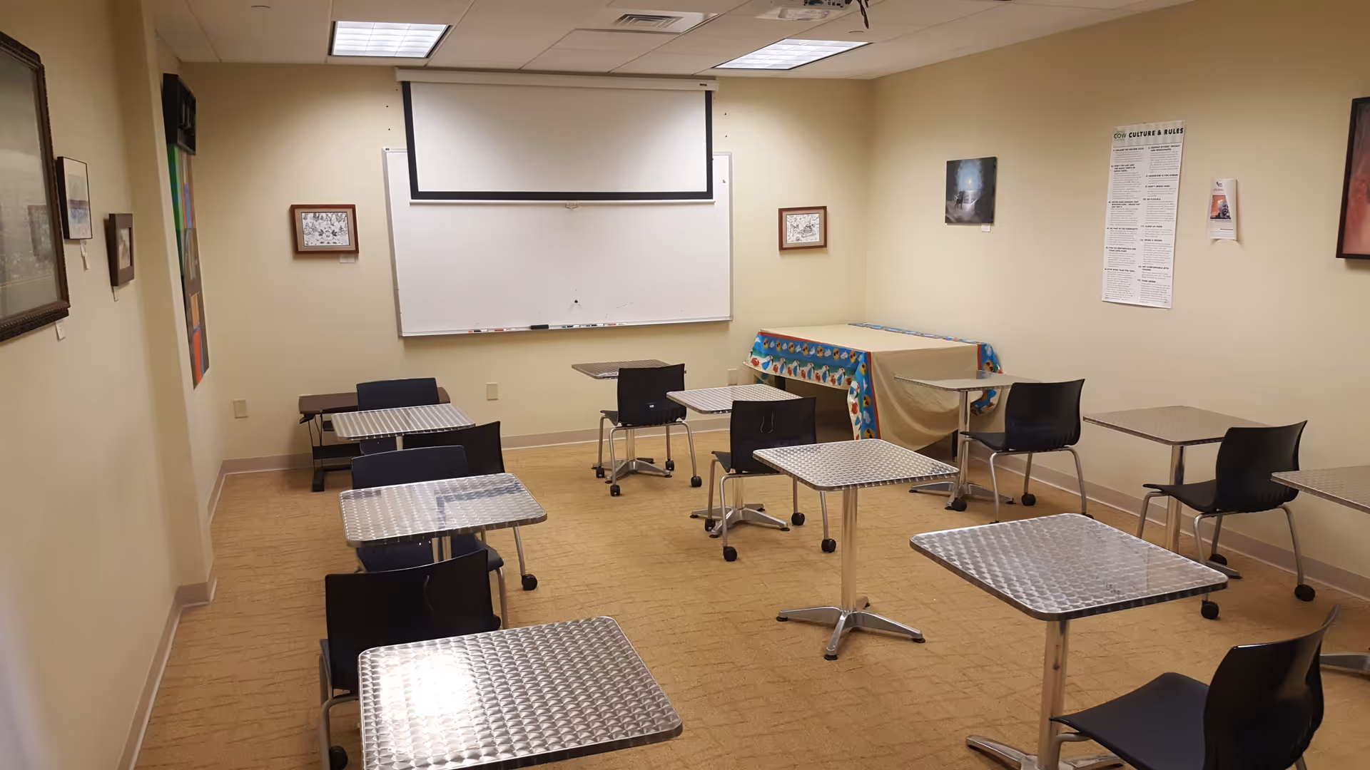 An empty interior activity room with metal-topped tables and chairs.