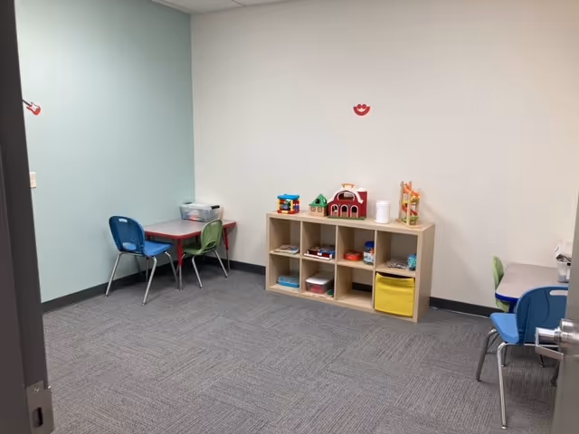A small playroom with cubby shelves, toy blocks, and child-sized tables and chairs.