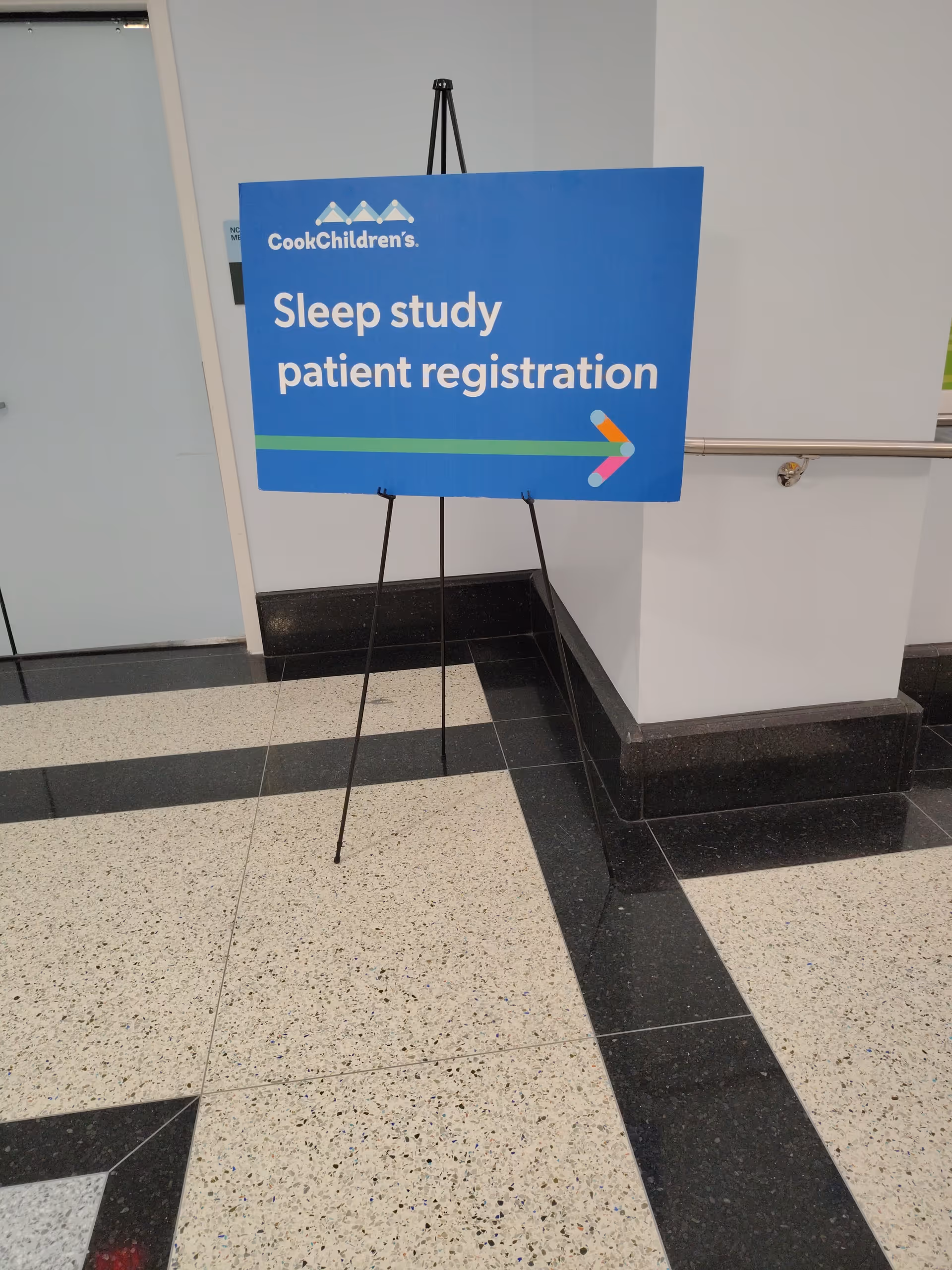 Blue sign reading Sleep study patient registration on an easel in an interior hallway.