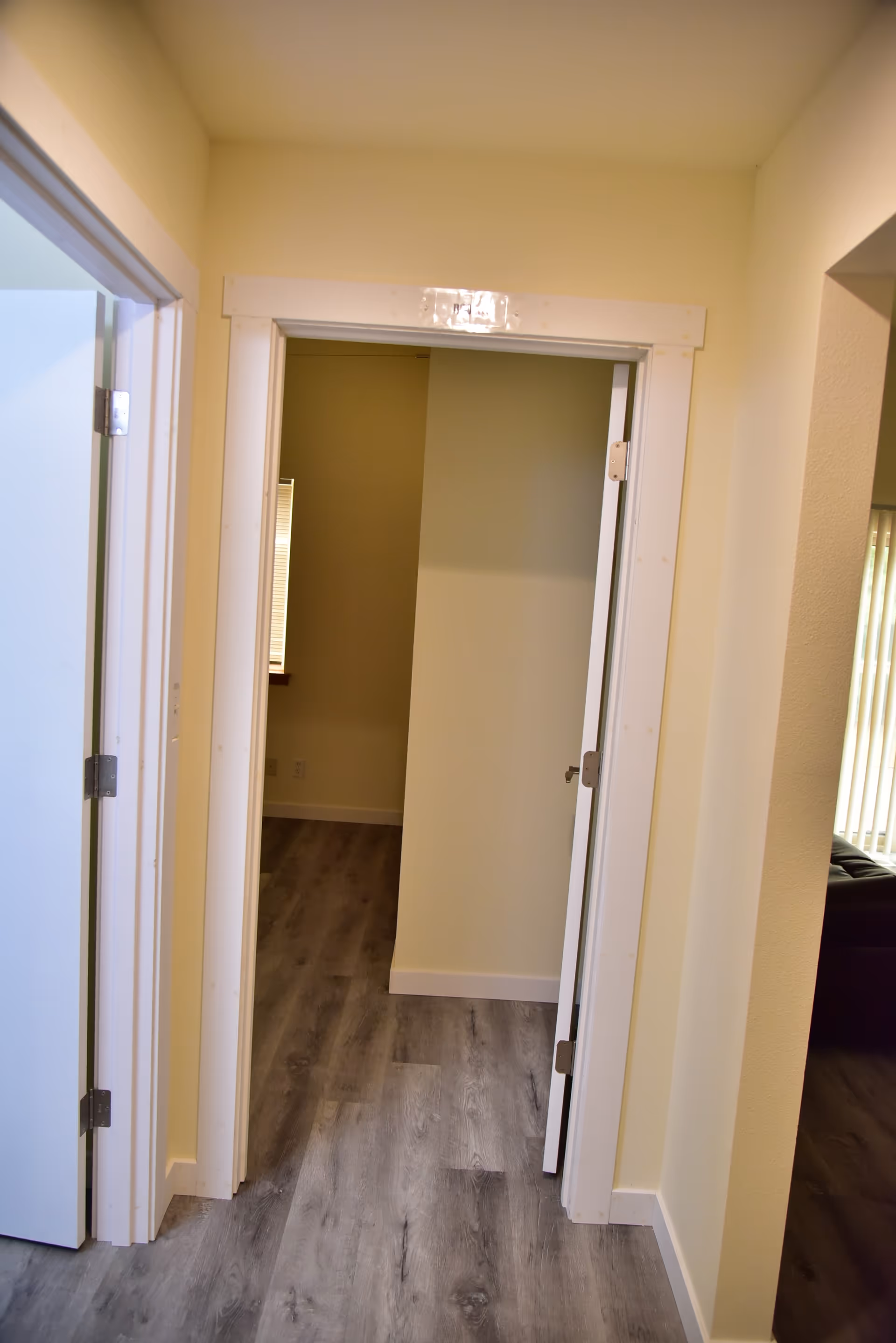 Bright hallway with open doors and beige walls in a residential facility.