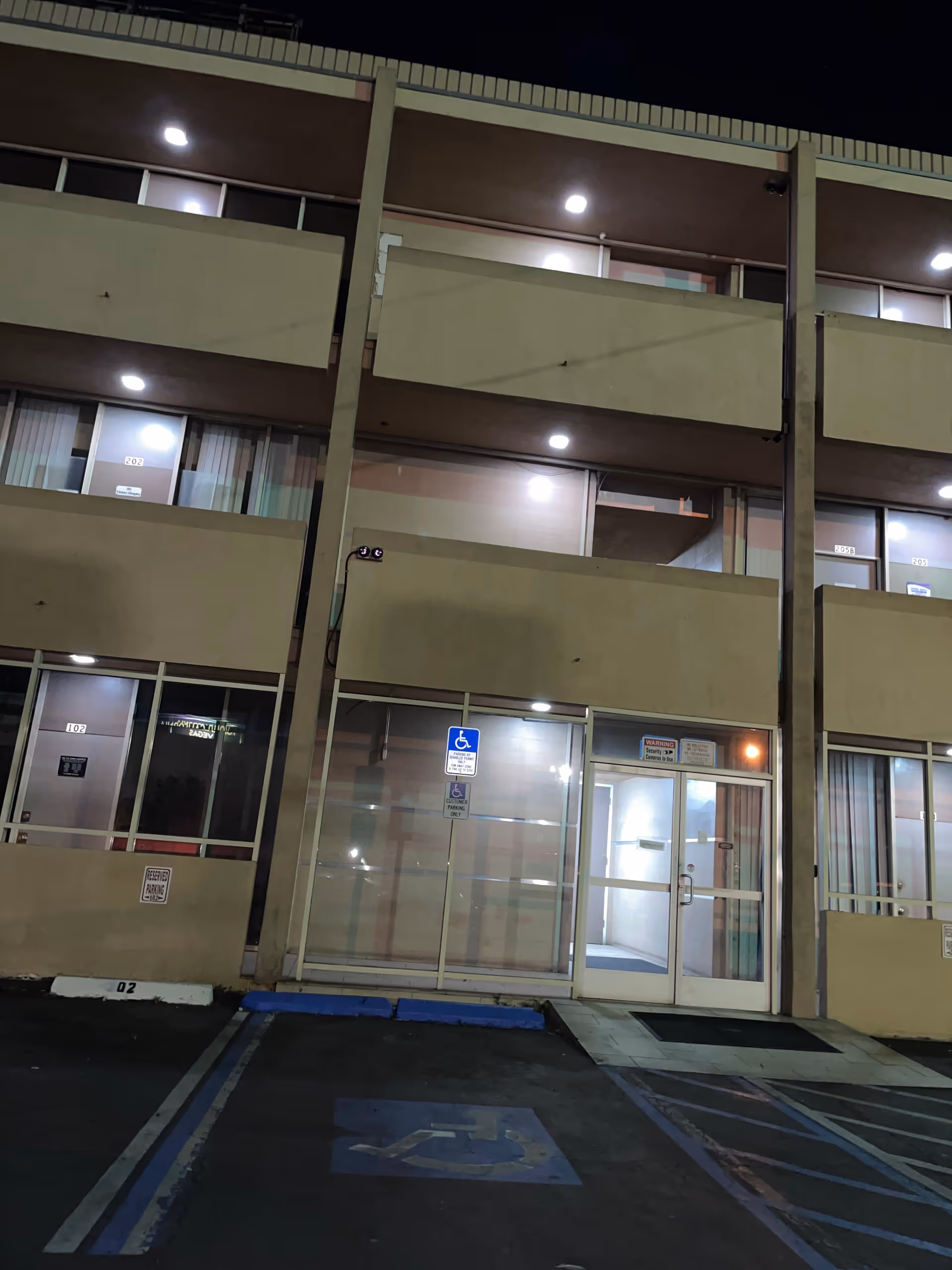 Night exterior of a senior living building with glass entrance doors
