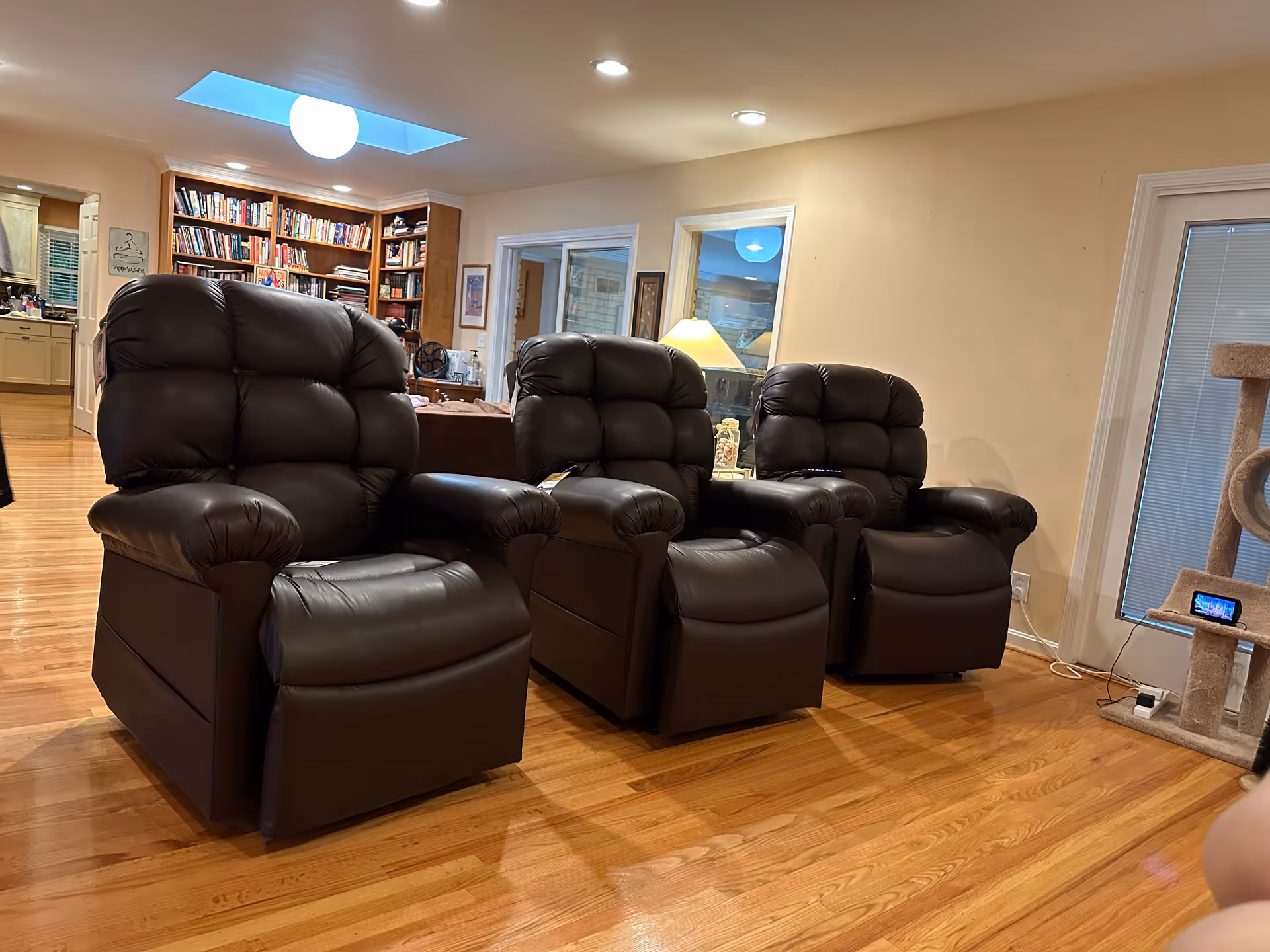 Three black leather recliners arranged in a senior living lounge with bookshelves
