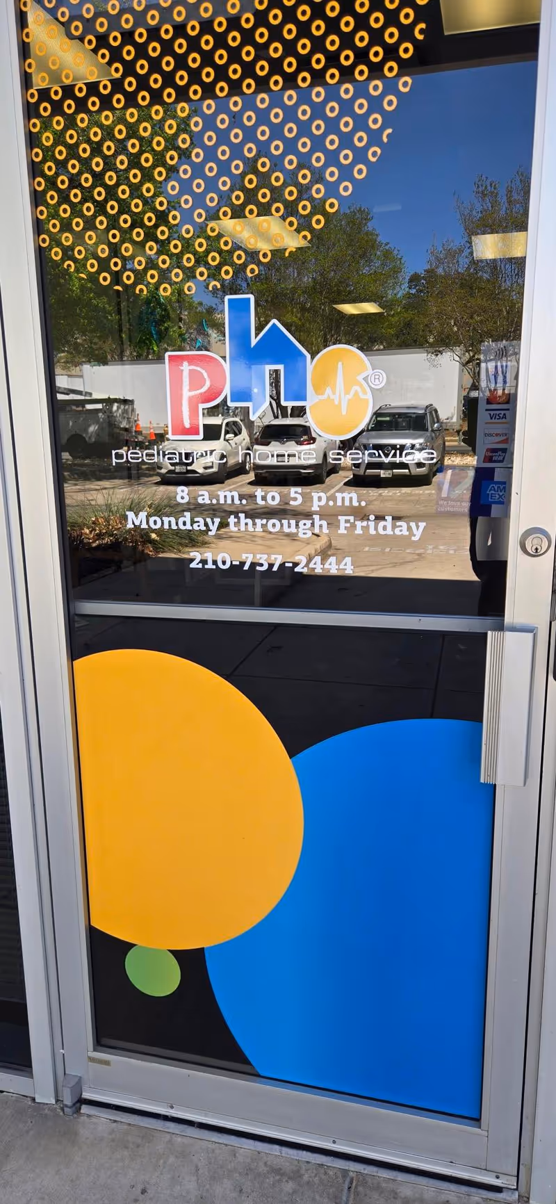 Glass door with Pediatric Home Service logo, hours, phone number, and colorful graphics.