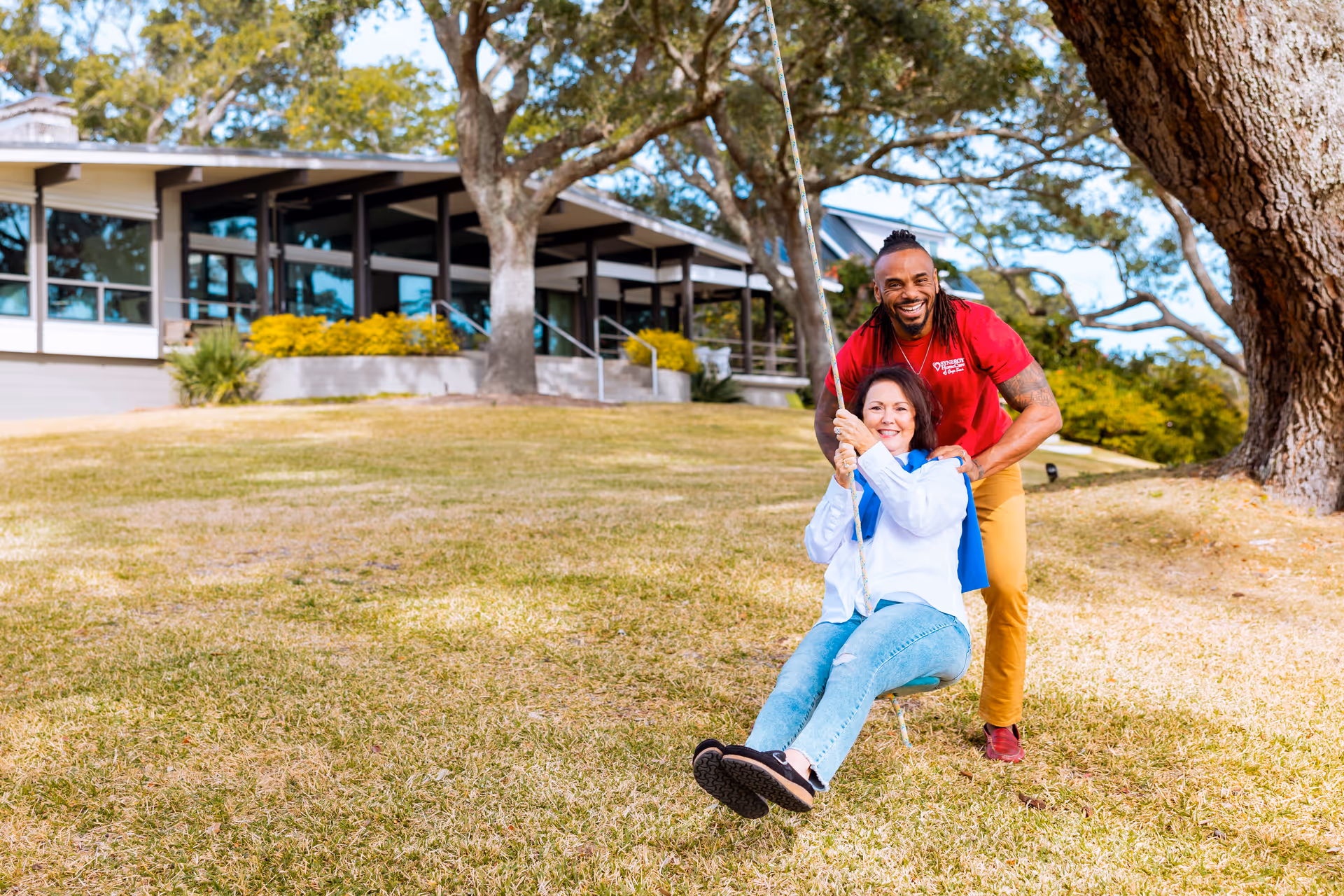 Caregiver from SYNERGY HomeCare assists a resident on a swing outdoors at the facility.