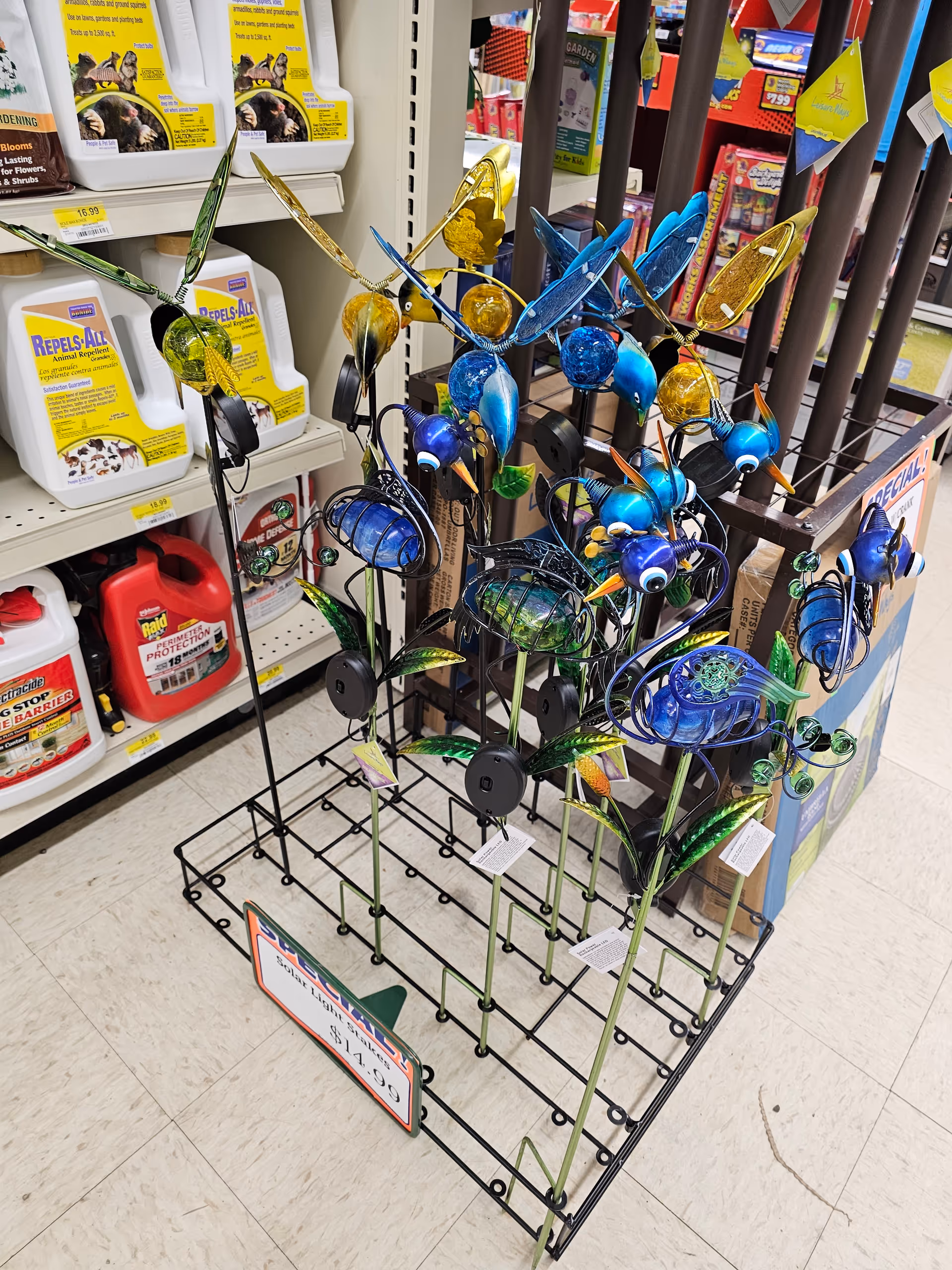 Colorful metal garden stake ornaments displayed on a rack inside a Discount Drug Mart.