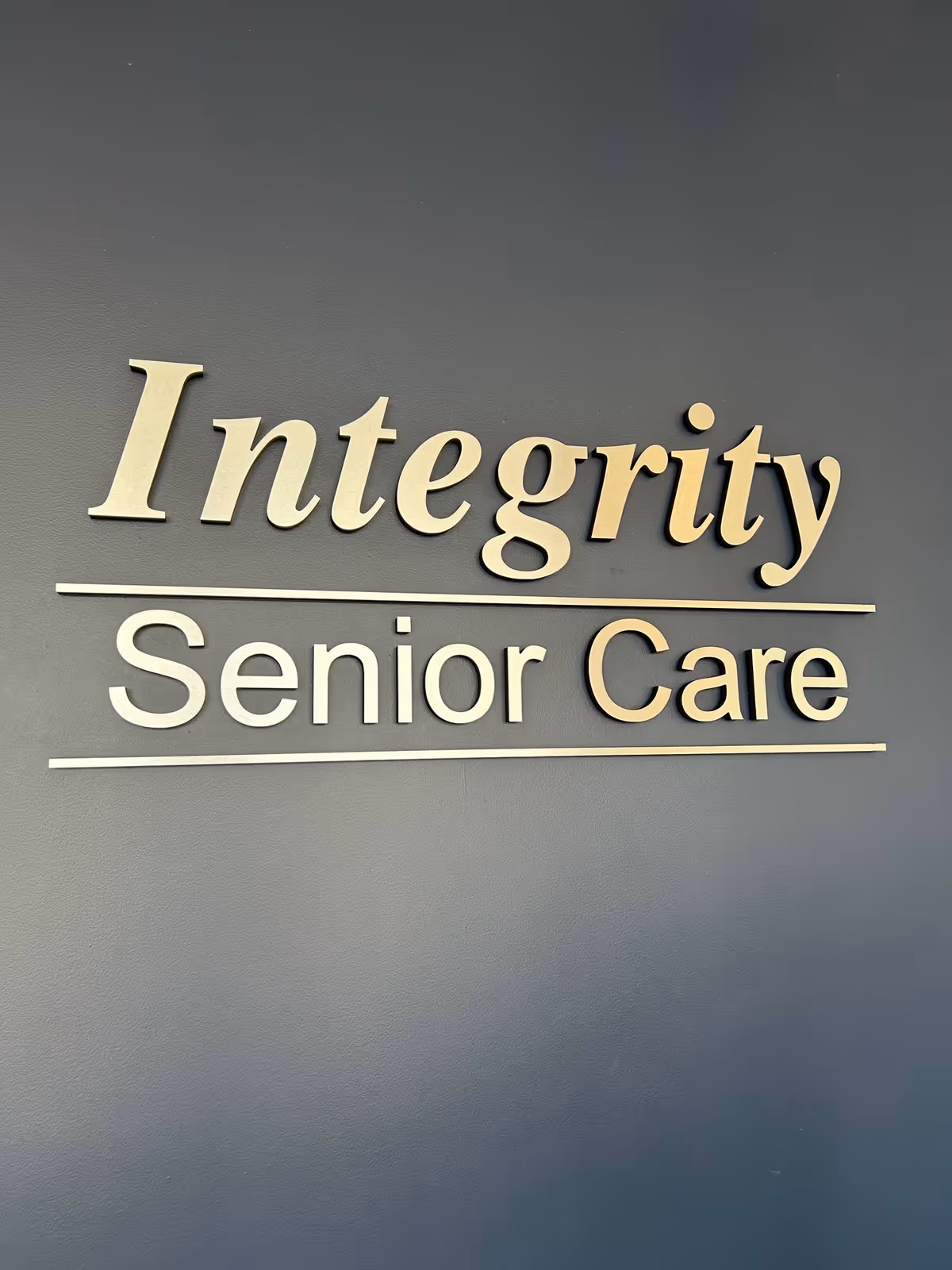 A gray interior wall with beige Integrity Senior Care sign and lines.