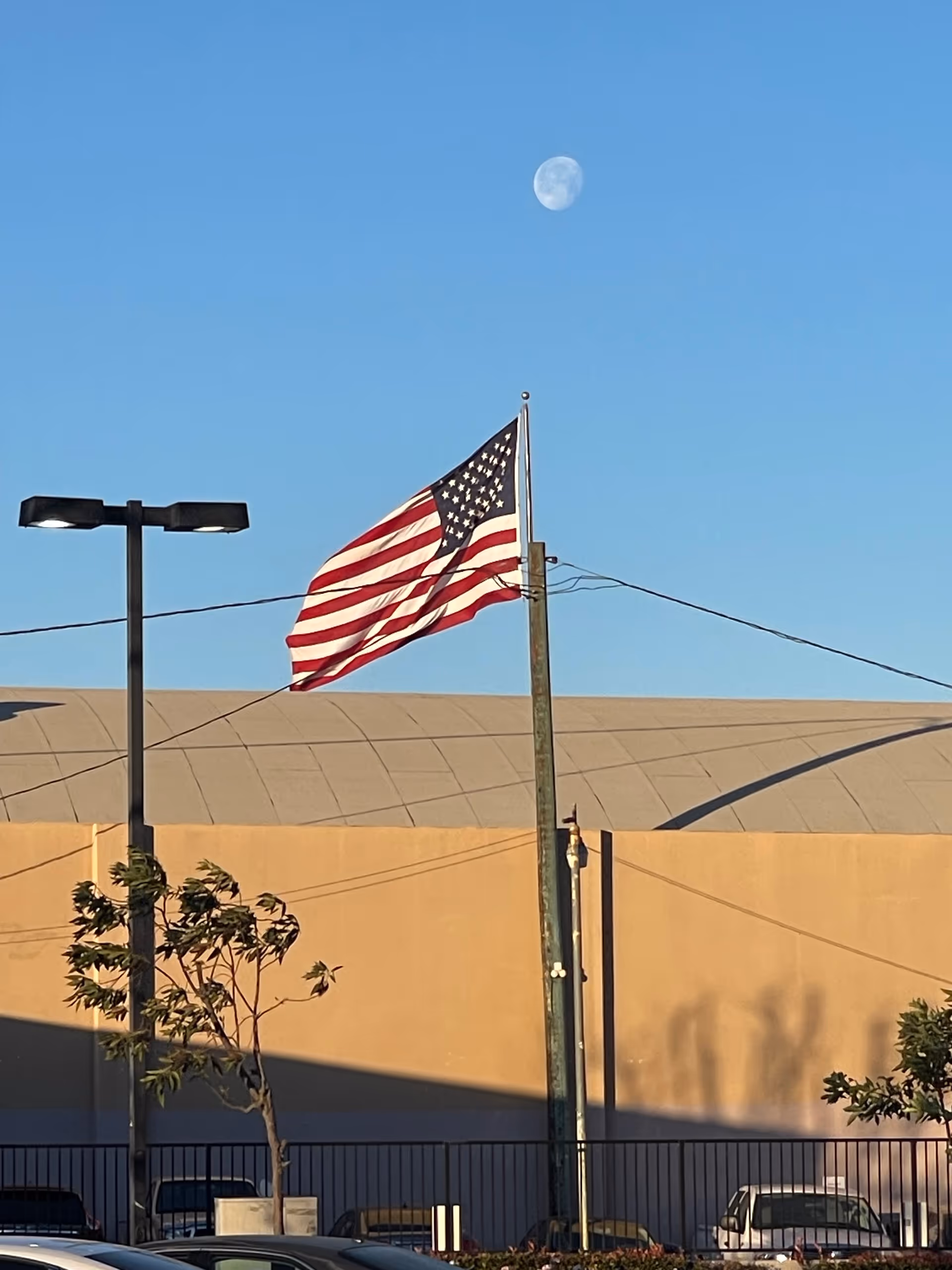 American flag on a pole in front of a beige building under a blue moonlit sky.