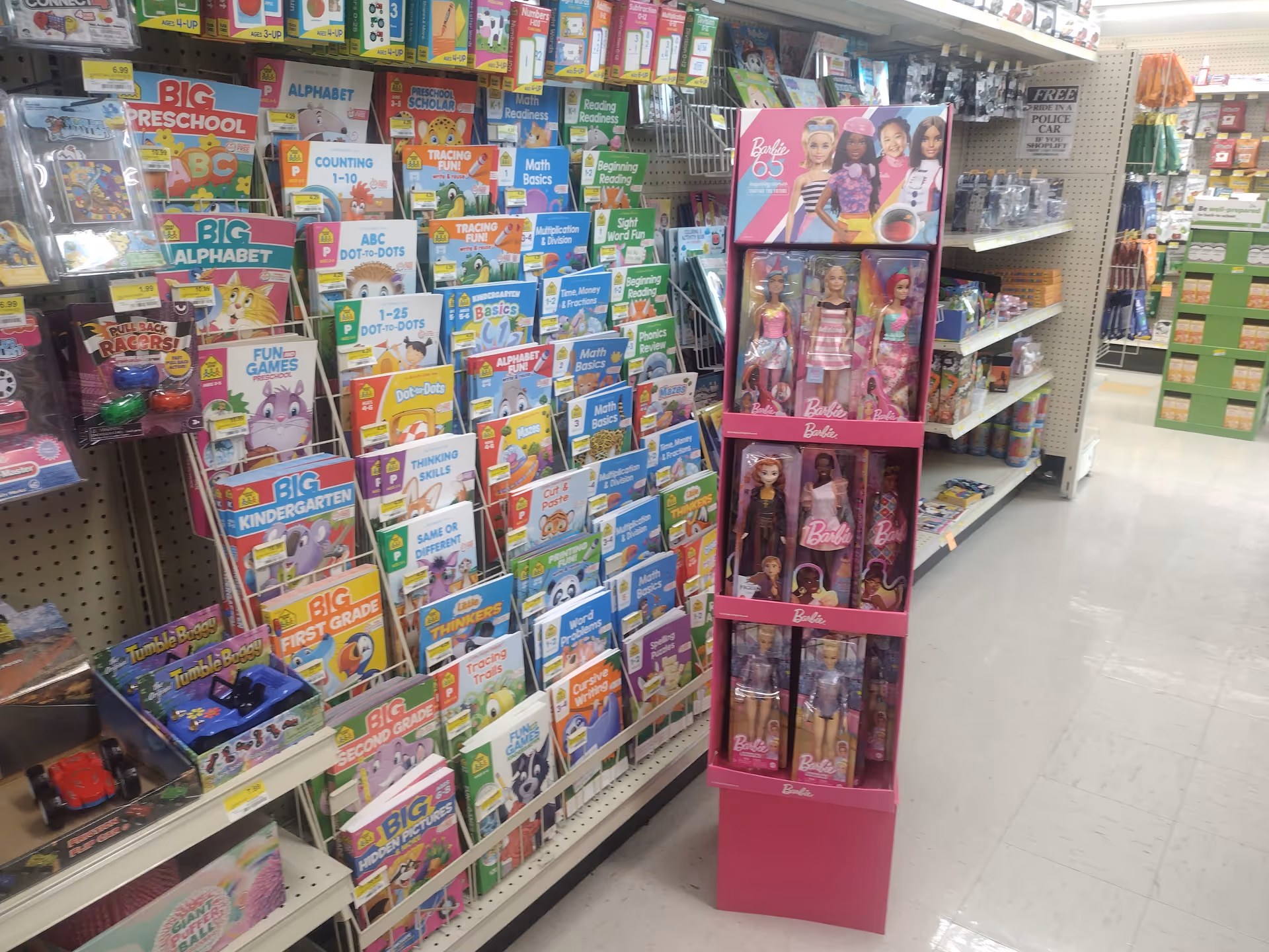 Retail store aisle with colorful children's books and a pink Barbie display.