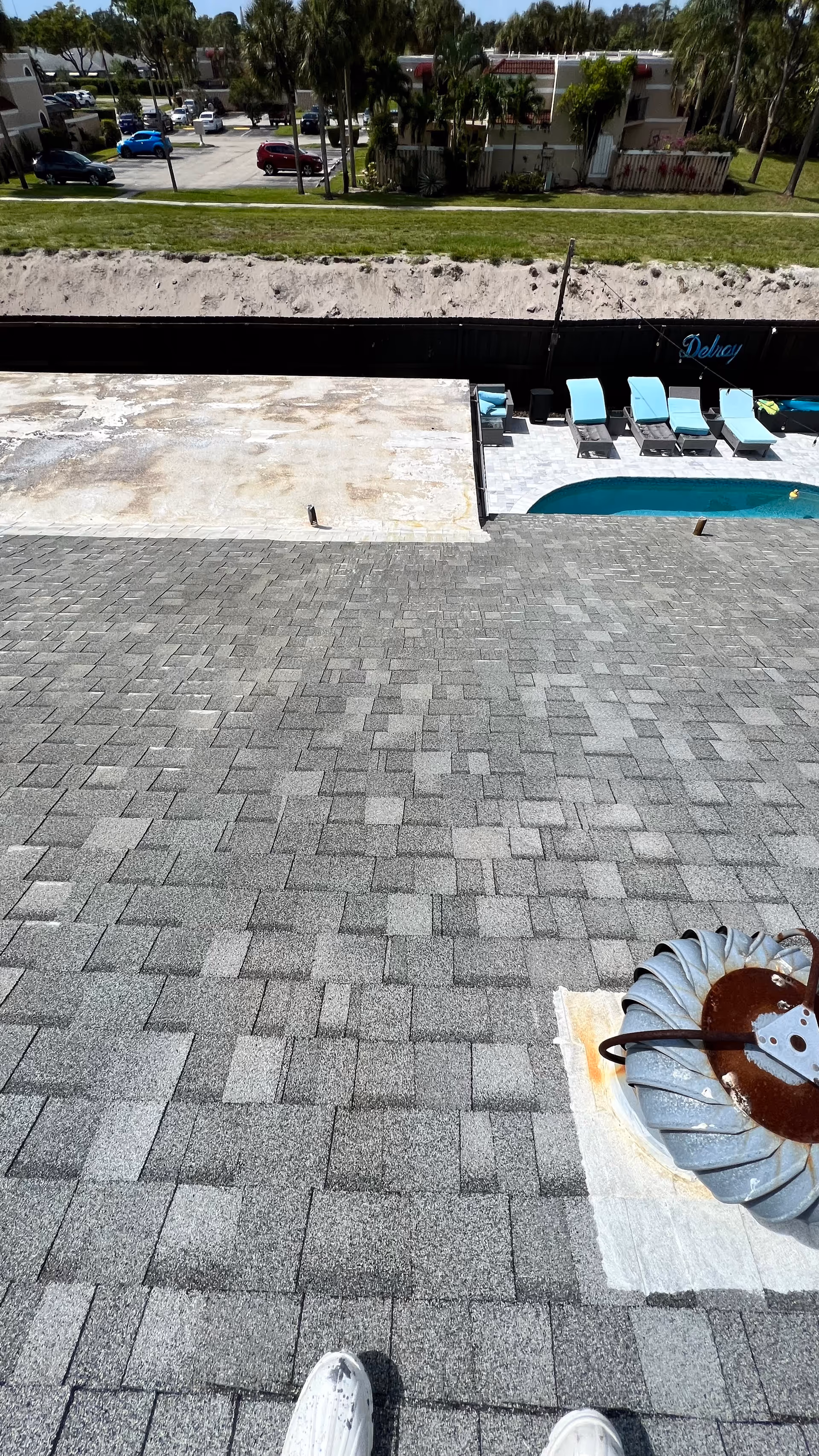 Aerial view of a rooftop pool area with blue lounge chairs.