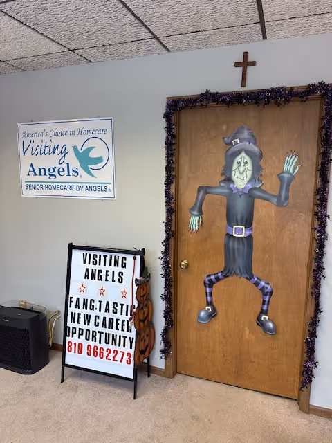 Interior hallway with a decorated door, garland, and Visiting Angels sign on the wall.