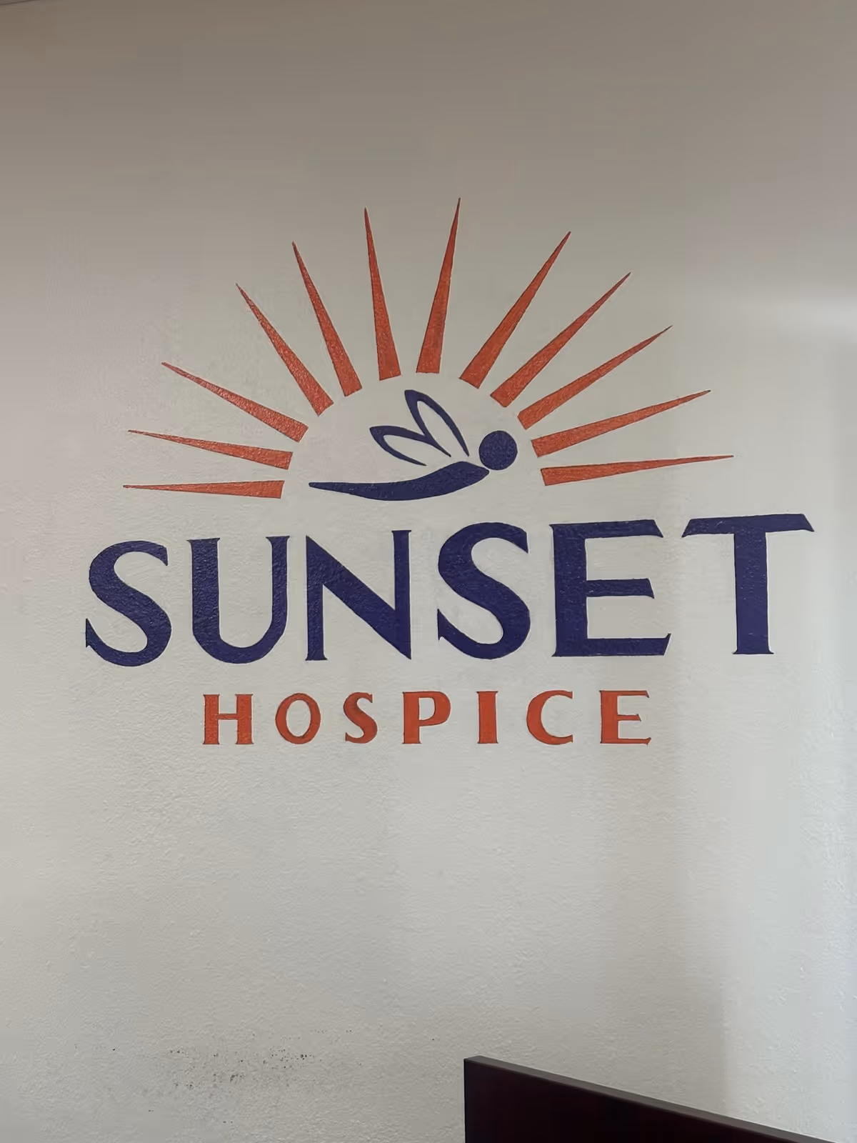 Interior wall featuring Sunset Hospice logo with sunburst graphic.