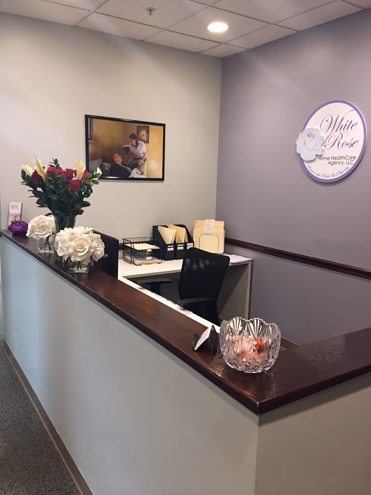 Reception desk with flowers and a White Rose sign in a care agency office.
