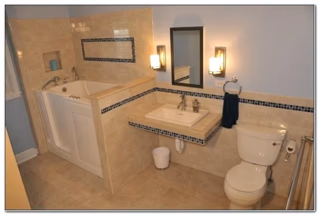 Accessible bathroom with tub, sink, mirror, toilet, and tiled decor.