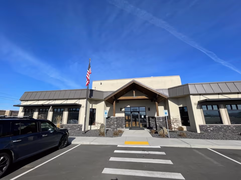 Exterior view of a modern senior living facility with a prominent entrance and flagpole