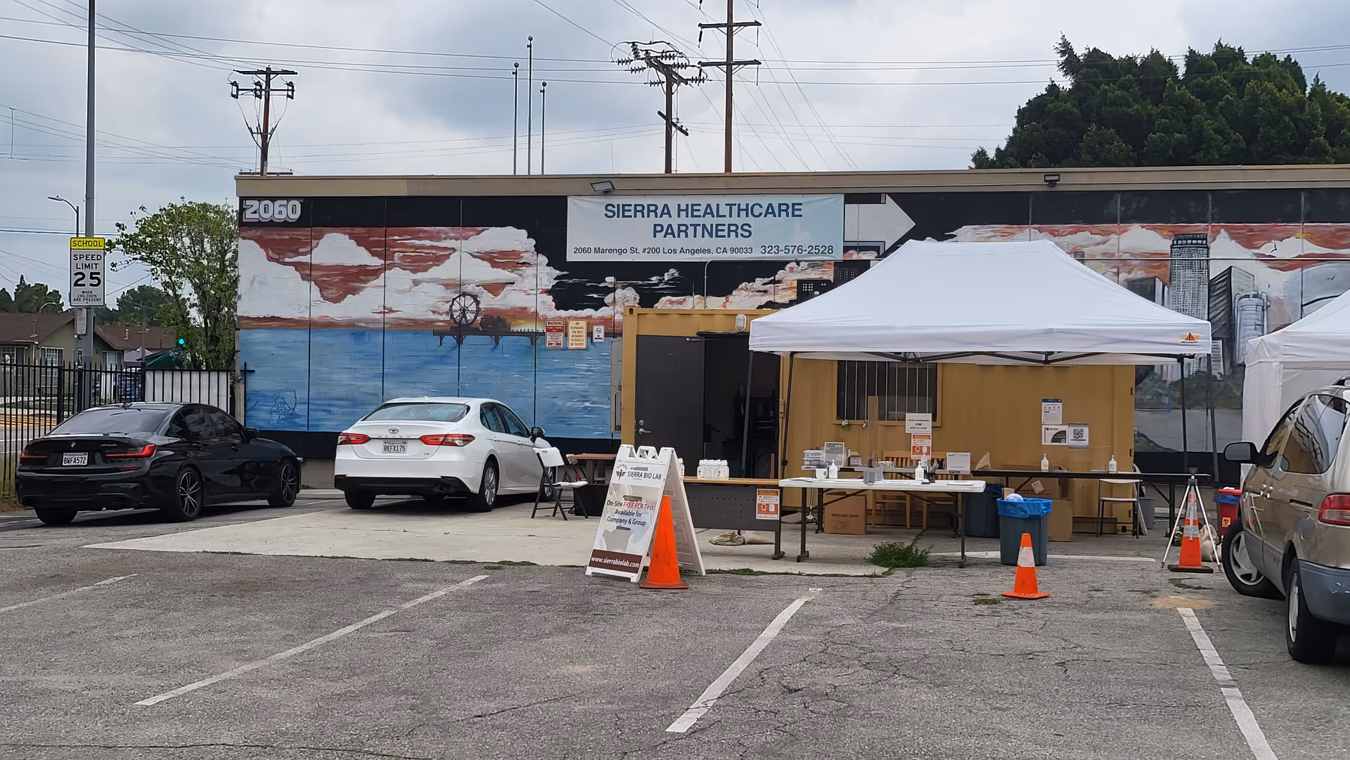 Exterior of Sierra Healthcare Partners building with a white canopy tent and parked cars.