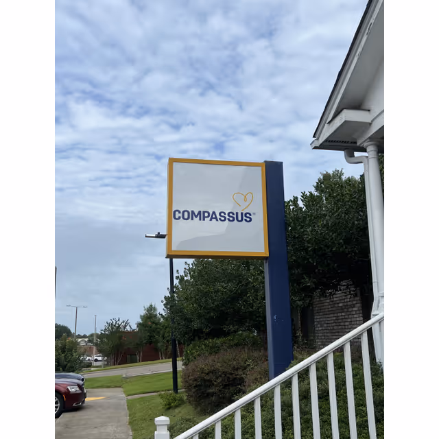 Compassus exterior sign mounted by a blue pillar near the facility entrance.