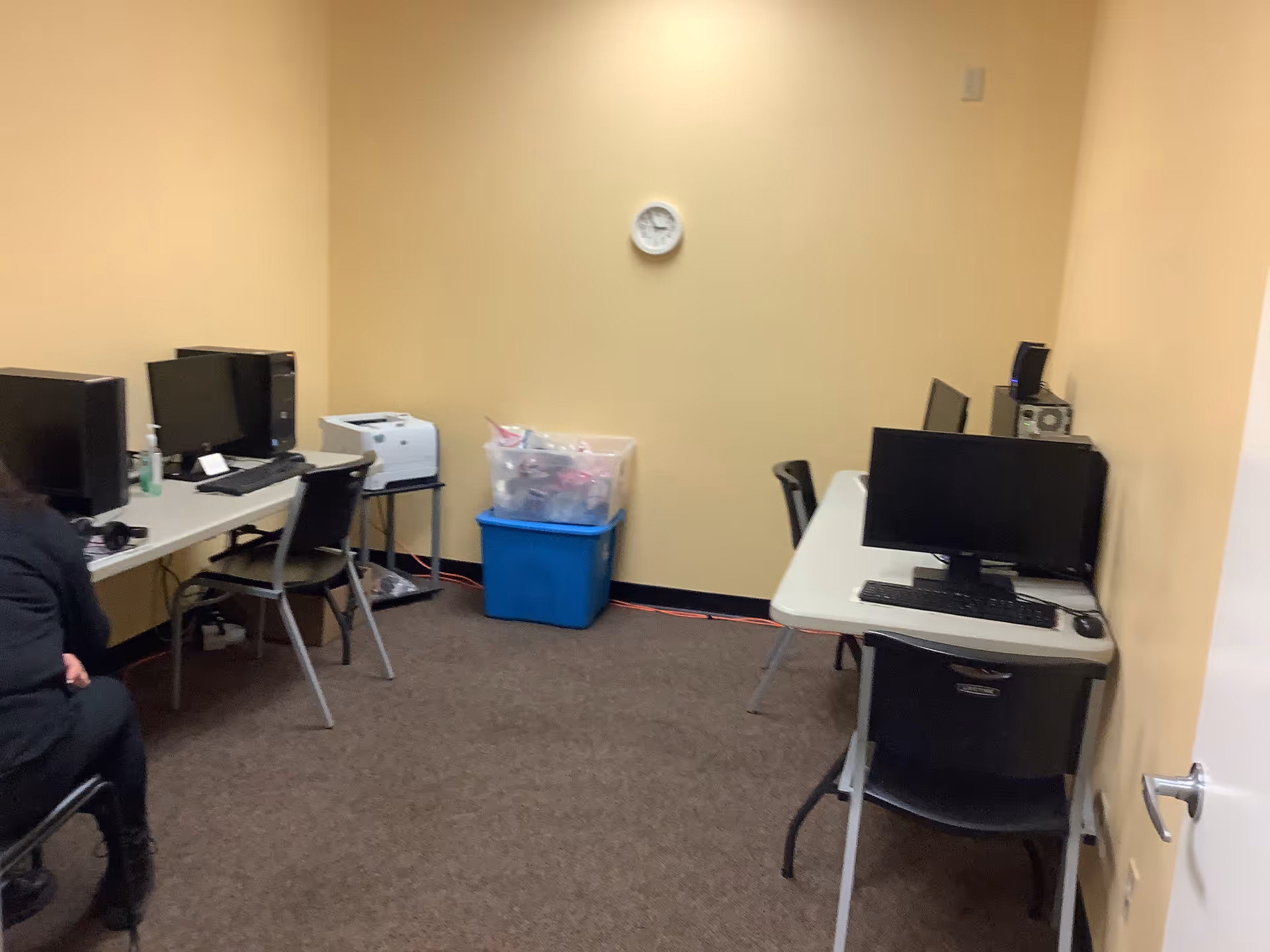 Office-style room with multiple computer desks and a printer inside Help at Home facility.