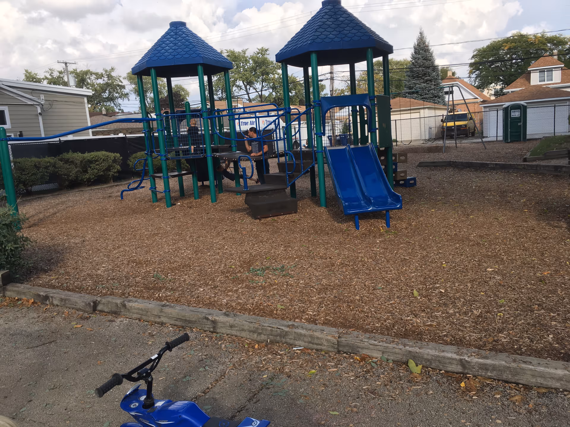 Outdoor playground with blue slides and climbing structures at a senior home.