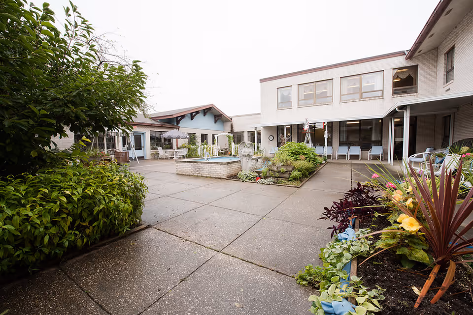 Outdoor courtyard at Wellspring Frankenmuth Hospice with greenery, seating, and a central fountain.