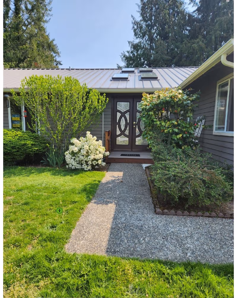 Front entrance of Mukilteo Green House featuring a gravel path, plants, and double doors.