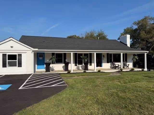 Single-story BrightStar Care building front with blue door, porch seating, planters.