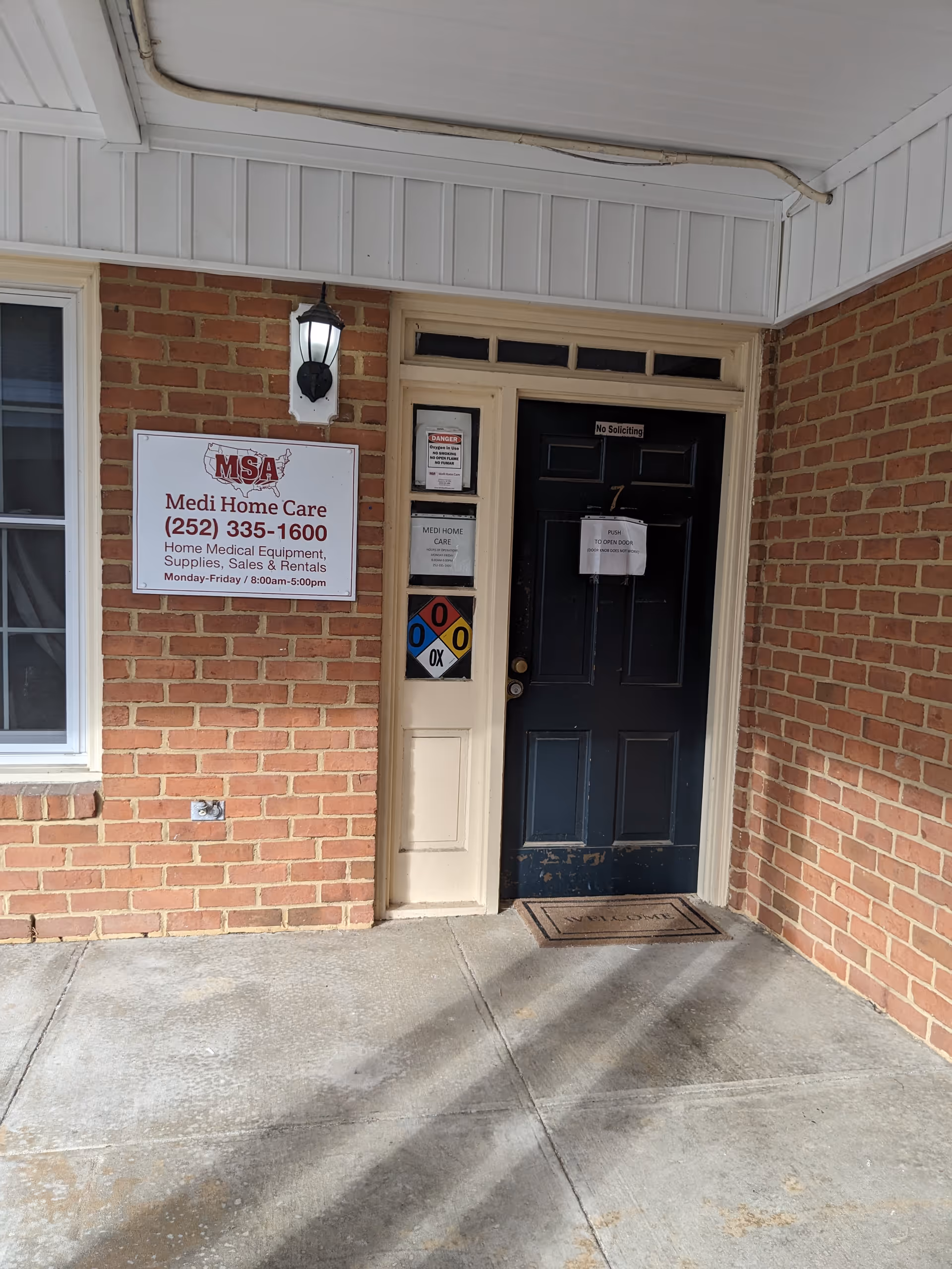 Brick exterior entrance with Medi Home Care signs and a black front door.