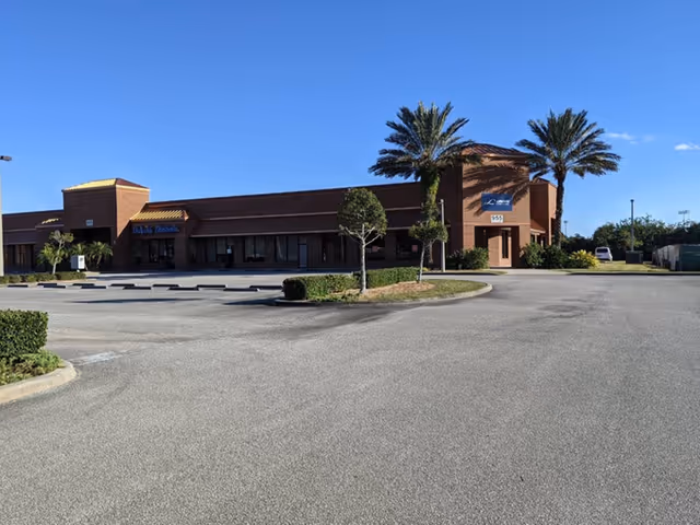 Exterior view of LINCARE senior living facility with a parking lot and palm trees.