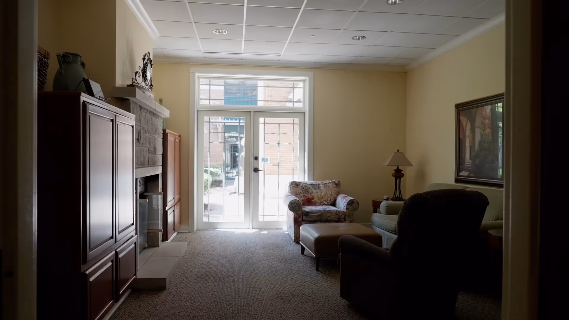 Bright living room with seating, a fireplace, and a glass door entry.