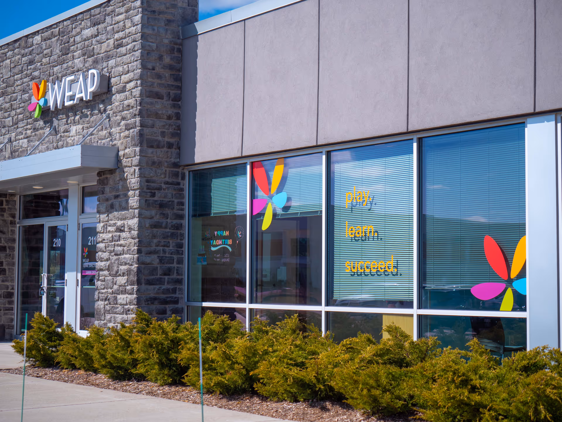 Exterior view of Wisconsin Early Autism Project (WEAP) facility with stone facade, windows, and landscaping.