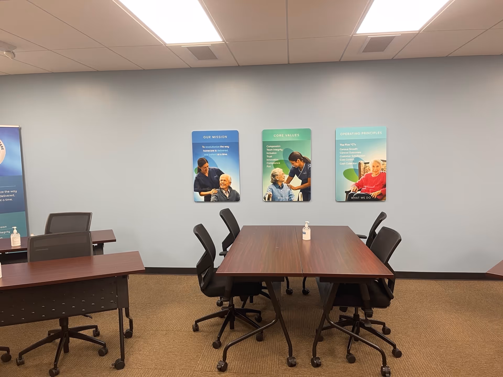 Conference room with long wooden tables, rolling chairs, and wall posters.