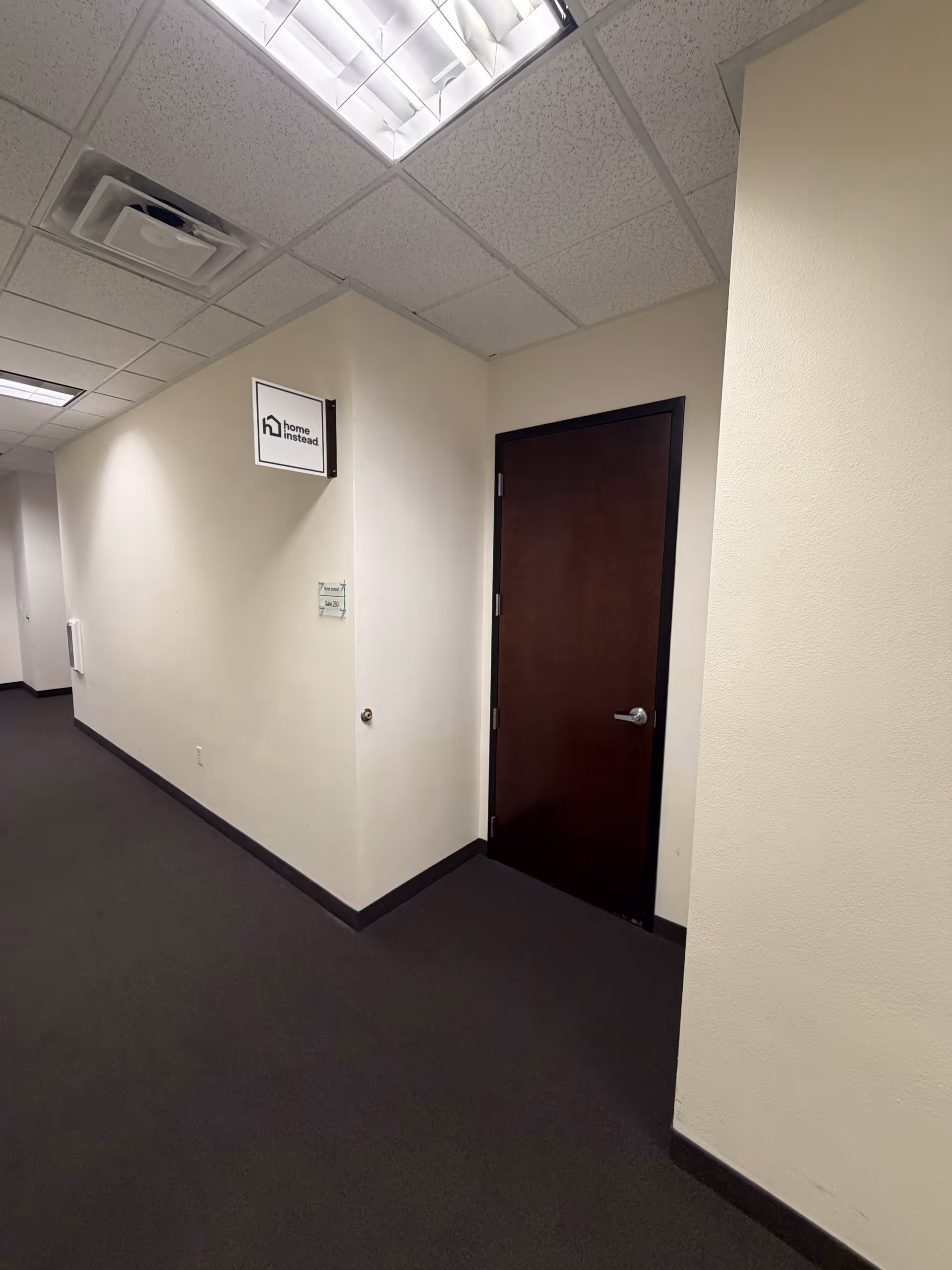 Interior hallway of a Home Instead facility with a brown wooden door.