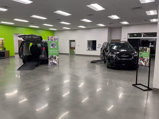 Indoor showroom with two mobility vans on display and ramps.