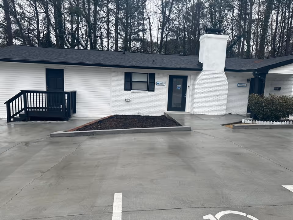 Exterior view of a white brick Procare Healthcare building with a parking lot.