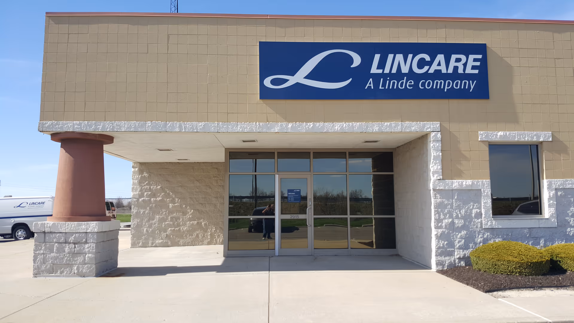 Exterior view of the LINCARE building entrance with glass doors and a blue sign.