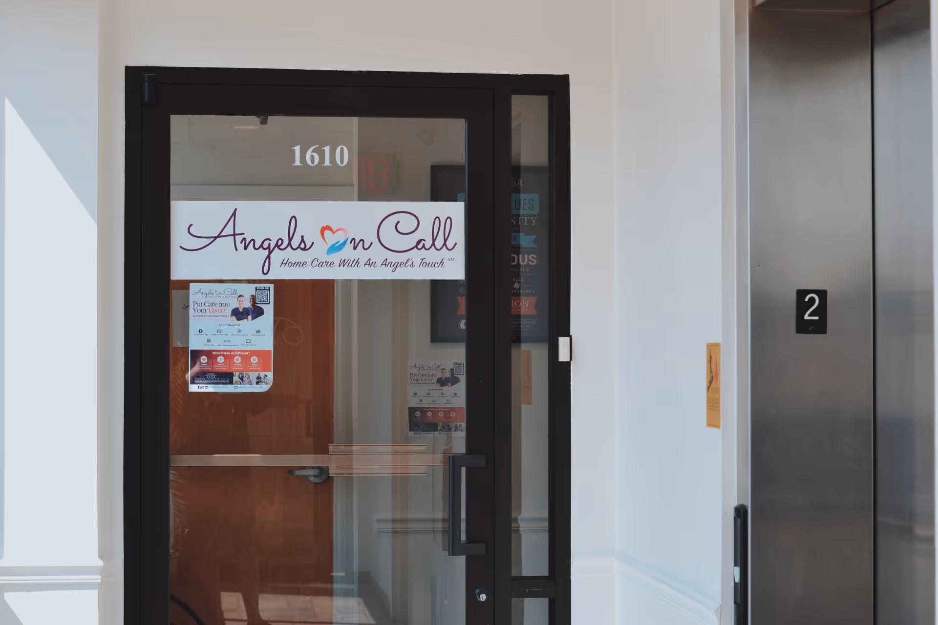 Glass door entrance with Angels On Call sign, hallway, and elevator on the right.
