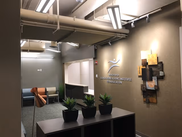 Reception area of a medical facility with seating, plants, and wall art.