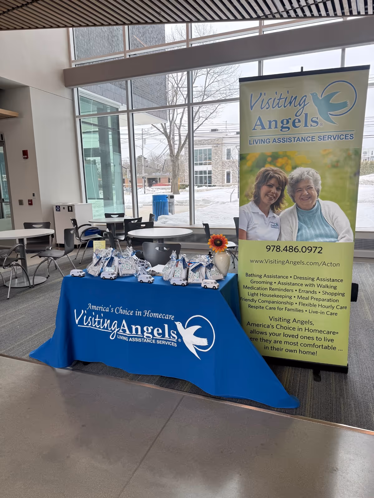Indoor lobby featuring a blue Visiting Angels table and a large promotional banner.