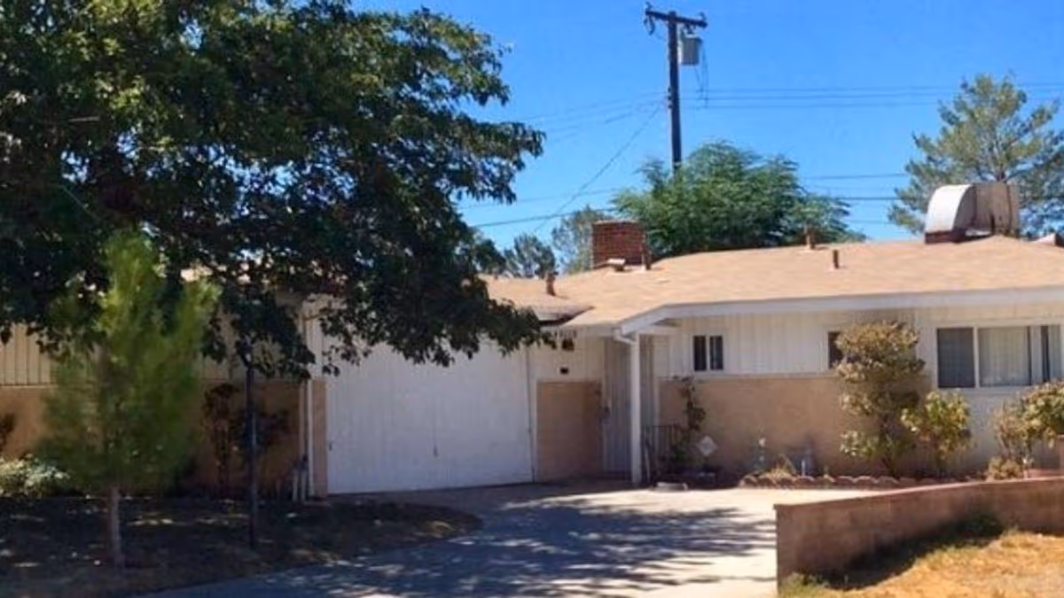 Front exterior of a single-story senior facility with driveway and white garage door.
