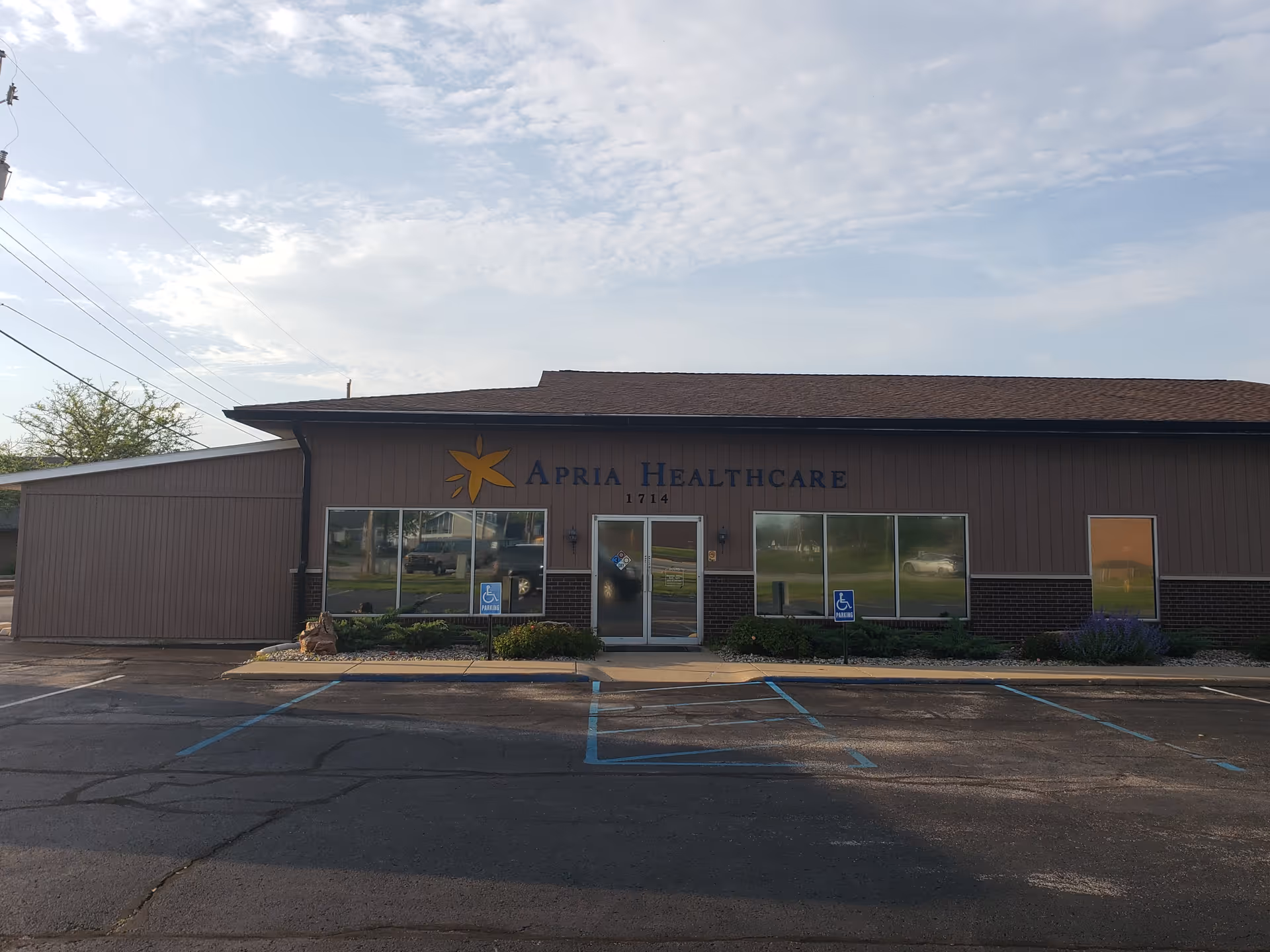 Front view of Apria Healthcare facility with large windows and a parking lot.
